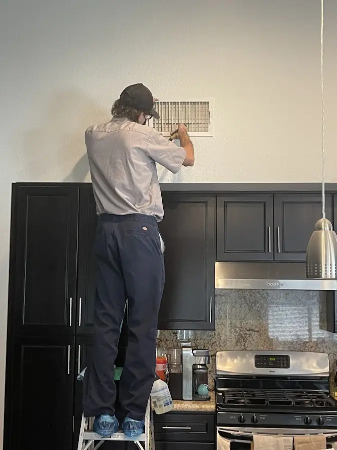 Technician inspecting an air vent during HVAC service in Lakewood
